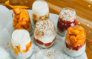 Colorful fruit and yogurt parfaits in glasses with oats, perfect for a healthy breakfast.