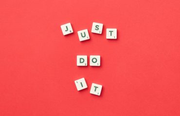 Motivational phrase 'Just Do It' spelled with Scrabble letters on a red background.